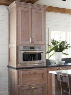 a kitchen with an oven, microwave and table in the corner by the wall is white shiping