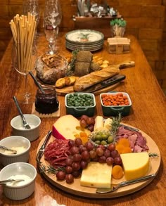 a wooden table topped with lots of different types of cheese and meats on top of it