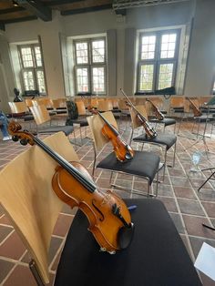 a room filled with lots of chairs and violin on top of each other in front of windows