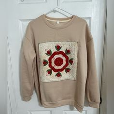 a sweater hanging on a door with a rose appliqued on the front