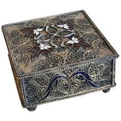 an ornate silver box with blue and white designs on it's sides, sitting on a white surface