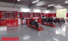 two motorcycles are parked in a garage with red workbenches and tools on the wall