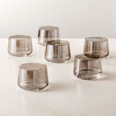 several clear glass cups sitting on top of a white countertop next to each other