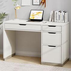 a white desk with two drawers and a laptop on it, next to a potted plant