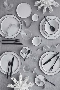 the table is set with black and white plates, silverware, and snowflakes