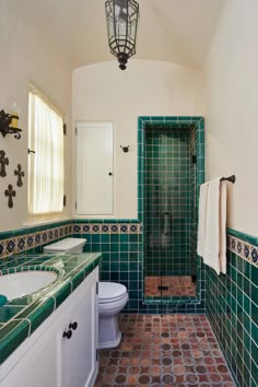 a bathroom with green and brown tiles on the walls