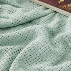 a book laying on top of a bed next to a green comforter and blanket