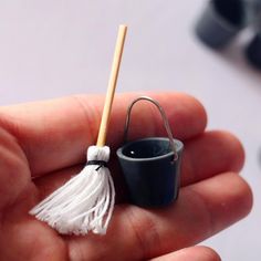 a miniature bucket with a tassel in the palm of someone's hand