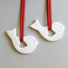 two white ceramic birds hanging from red ribbon