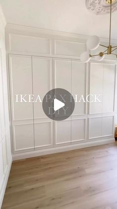 an empty room with wooden floors and white walls, in front of a chandelier