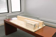 a wooden table topped with two stacks of wood blocks on top of each other in an empty room