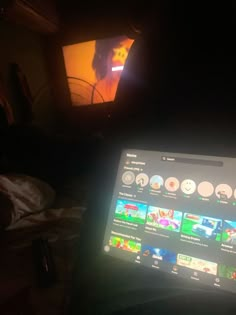 an open laptop computer sitting on top of a bed in front of a flat screen tv