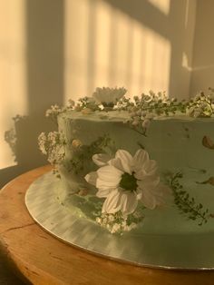 there is a green cake with white flowers on the top and leaves on the bottom