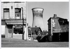 black and white photograph of an industrial building with a cooling tower in the back ground