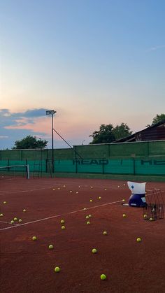 tennis balls are scattered on the court as the sun sets