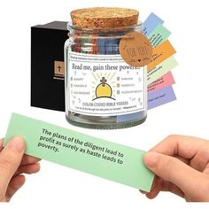 a person holding up a card with a message in it next to a jar filled with magnets