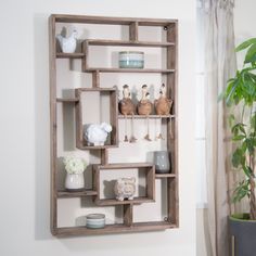 a wooden shelf with vases and other items on it next to a potted plant