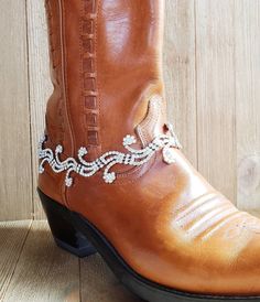 a pair of cowboy boots with beading on the side, sitting on a wooden floor