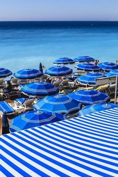 many blue and white umbrellas are on the beach