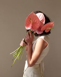 a woman with flowers in her hair holding it up to her face