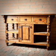 a wooden sideboard with drawers and shelves on brick flooring next to a brick wall