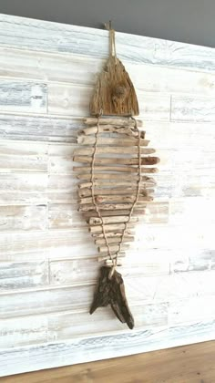 a fish made out of driftwood hanging on a wall next to a wooden hook