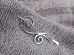 I created this elegant swirly shawl pin out of sturdy German silver wire. It has a medium size and is suitable for all knitted and loose fiber fabrics. The metal is hammered to add to its beauty and strength.  Material / Finish: German silver (photo 1-3) Sterling silver / Bare (photo 4) Sterling silver / Antique (photo 5) Copper / Bare  (photo 6) Copper / Antique (photo 7) Brass (photo 8) The pin measures about 2.3 inches (5.7 cm).  Pointed stick is around  3 inches.  I take great care and atten Modern Shawl, Silver Shawl, Julia Jones, Shawl Pin, Leather Corded Necklace, Scarf Pin, Spiral Earrings, Wire Work Jewelry, Shawl Pins