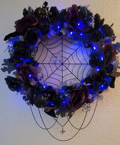 a spider web decorated with blue lights and flowers in the center is surrounded by black roses