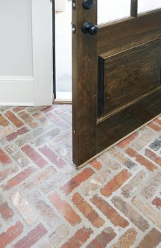 an open wooden door on a brick floor