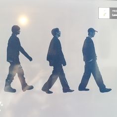 the silhouettes of three men are walking together