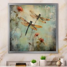 three dragonflies flying over flowers on a wall