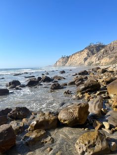 rocks and water on the beach with mountains in the background