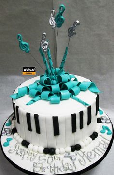 a birthday cake decorated with musical notes and blue ribbon on the top is a piano