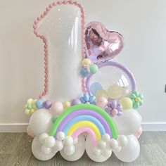 an assortment of balloons and decorations in front of a white vase with a heart shaped balloon