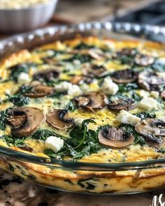 an omelet with spinach, cheese and mushrooms in a glass dish on a table