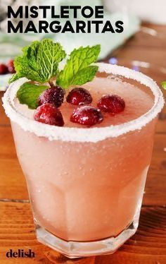 a drink with ice and cranberries in it on a table next to mint leaves