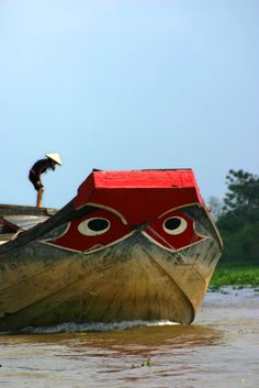 a man standing on top of a wooden boat in the middle of water with an umbrella over his head