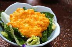 a bowl filled with lettuce and cheese on top of a table