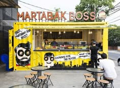 people are sitting at tables in front of a food truck with graffiti on the side