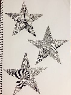 three stars are drawn in black and white on a spiral bound notebook, each with an intricate design