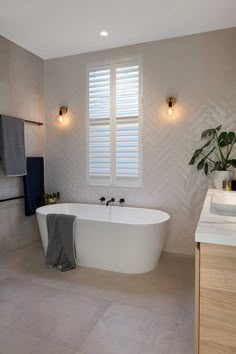 a white bath tub sitting next to a window in a bathroom