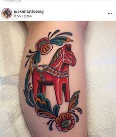 a horse tattoo on the leg of a woman's legs, with flowers and leaves around it