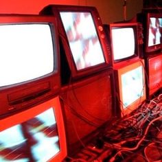 there are many televisions that have been turned on in the dark room with red lights