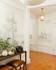 a room with white walls and wood flooring has a painting on the wall next to a bench