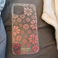 a case with pink flowers on it sitting on top of a bed next to a blanket