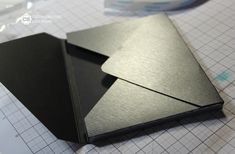 two pieces of metal are sitting on top of a cutting mat with scissors and tape