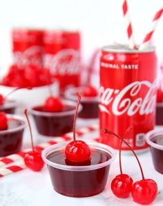 small cups filled with cherries next to a can of coca - cola