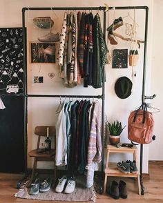 an organized closet with clothes and shoes hanging on the wall next to a blackboard