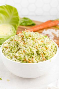 a white bowl filled with coleslaw next to carrots and lettuce