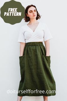 a woman standing in front of a white wall wearing a green skirt with pockets on the side